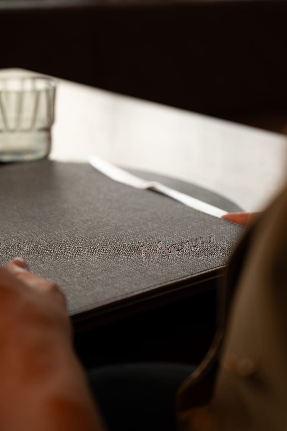 Hands opening La Raisc’s menu at a table in the restaurant. Photograph by Luca Canins.